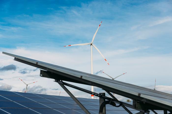 Bild des Windparks. Im Vordergrund Solarpanels im Bild